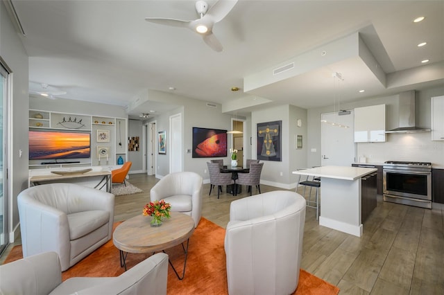 living area featuring light wood-type flooring, visible vents, recessed lighting, baseboards, and ceiling fan