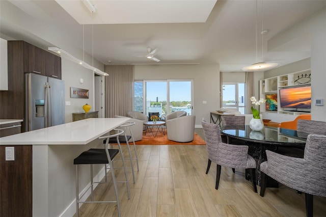 kitchen featuring a breakfast bar area, light wood-type flooring, stainless steel refrigerator with ice dispenser, modern cabinets, and open floor plan