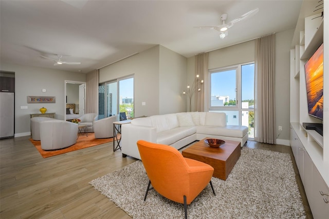 living area featuring a ceiling fan, wood finished floors, and baseboards