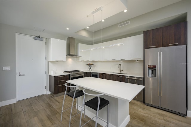 kitchen with visible vents, a sink, stainless steel appliances, dark brown cabinetry, and wall chimney range hood