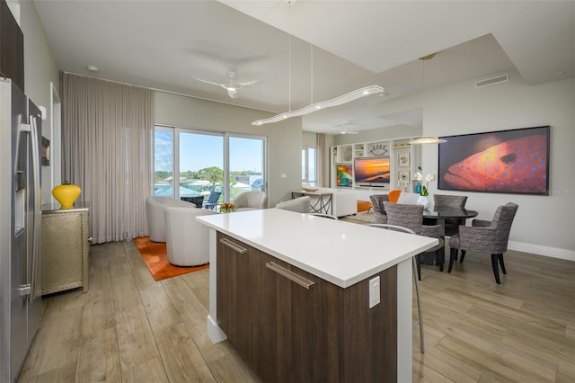 kitchen featuring light wood finished floors, ceiling fan, open floor plan, stainless steel fridge, and modern cabinets