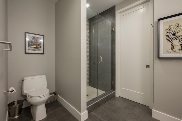 bathroom featuring tile patterned flooring, toilet, baseboards, and a stall shower