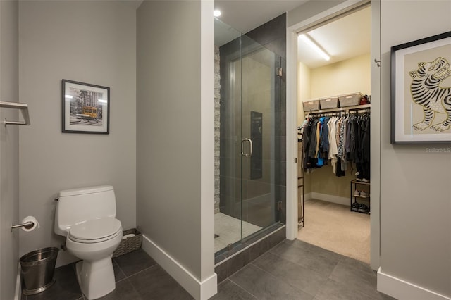 bathroom featuring toilet, baseboards, and a stall shower