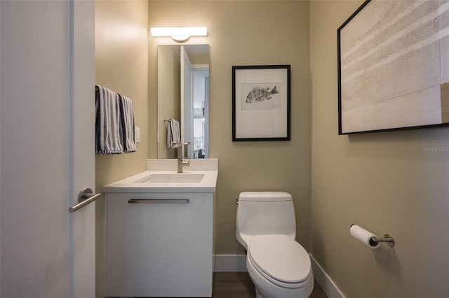 bathroom featuring vanity, toilet, and baseboards