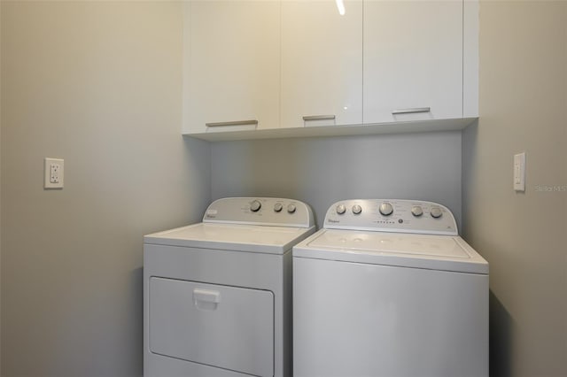 clothes washing area with washing machine and dryer and cabinet space