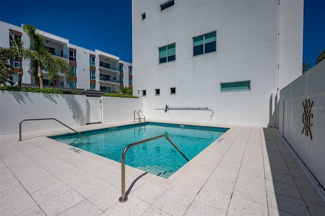 pool with a patio area and fence