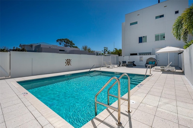 community pool with a patio and fence