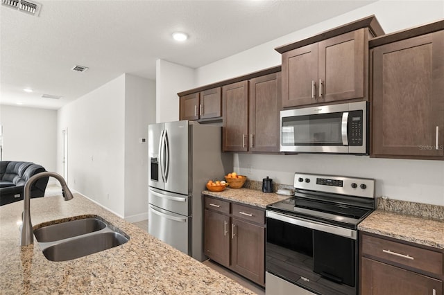 kitchen featuring visible vents, a sink, dark brown cabinets, appliances with stainless steel finishes, and open floor plan