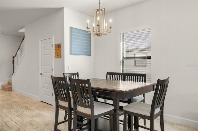 dining space featuring baseboards, an inviting chandelier, stairs, and light wood finished floors