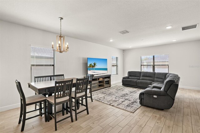 dining area featuring visible vents, light wood-type flooring, and a textured ceiling