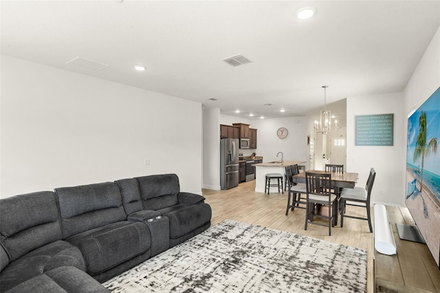 living room with a chandelier, visible vents, light wood-style flooring, and recessed lighting