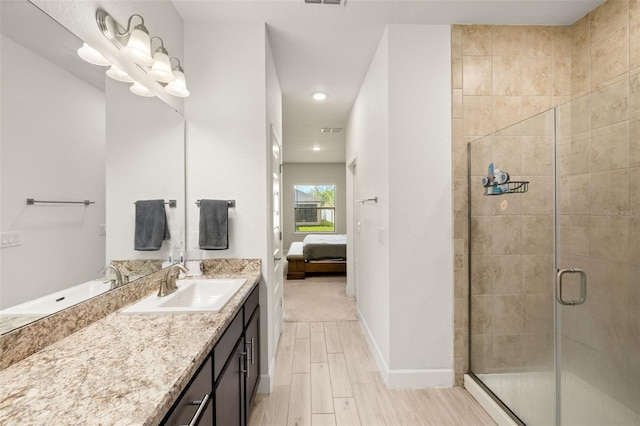 ensuite bathroom with wood finish floors, ensuite bathroom, a shower stall, baseboards, and vanity