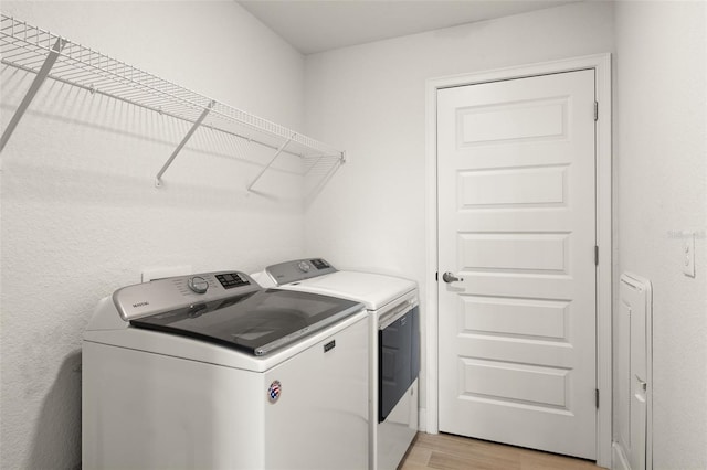 washroom featuring light wood finished floors, laundry area, and washing machine and clothes dryer