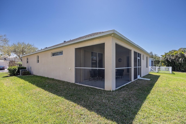 view of home's exterior featuring a lawn, a sunroom, and stucco siding