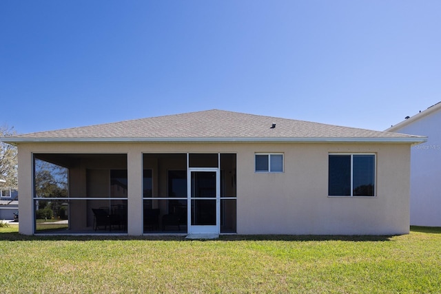 back of house featuring stucco siding, a lawn, a sunroom, and roof with shingles