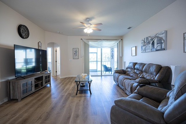 living area with wood finished floors, baseboards, visible vents, arched walkways, and ceiling fan