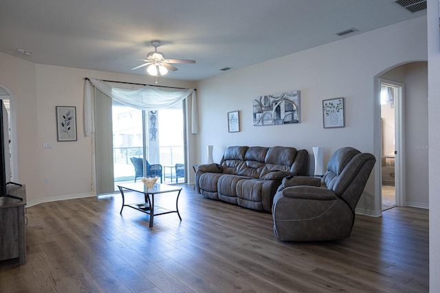 living area with visible vents, arched walkways, and dark wood-style floors