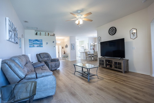 living area with visible vents, baseboards, wood finished floors, arched walkways, and a ceiling fan