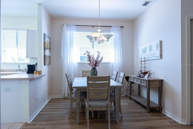 dining area featuring a notable chandelier, visible vents, baseboards, and wood finished floors