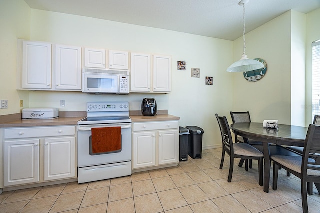 kitchen with light tile patterned floors, white appliances, pendant lighting, and white cabinetry