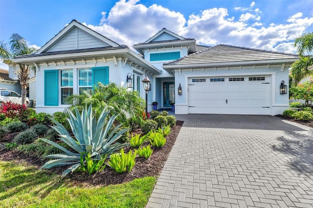 view of front of property with a tile roof, decorative driveway, an attached garage, and stucco siding