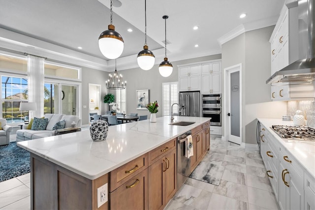 kitchen with ornamental molding, a sink, open floor plan, appliances with stainless steel finishes, and wall chimney exhaust hood