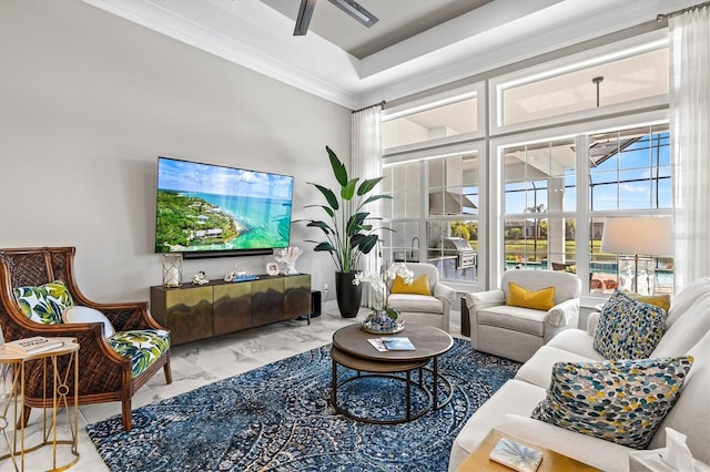 living area with ornamental molding, marble finish floor, and ceiling fan