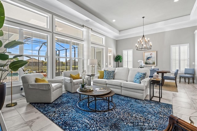 living room featuring a tray ceiling, baseboards, a notable chandelier, and a high ceiling