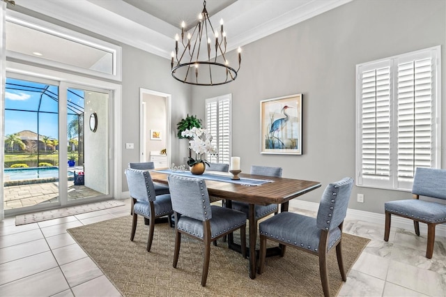 dining area with a chandelier, baseboards, a tray ceiling, and ornamental molding