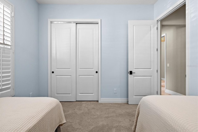 bedroom featuring a closet, light colored carpet, and baseboards