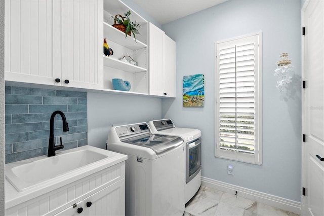 clothes washing area with baseboards, washing machine and dryer, cabinet space, marble finish floor, and a sink