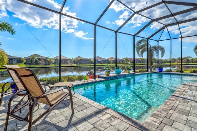 outdoor pool with glass enclosure, a patio, and a water view