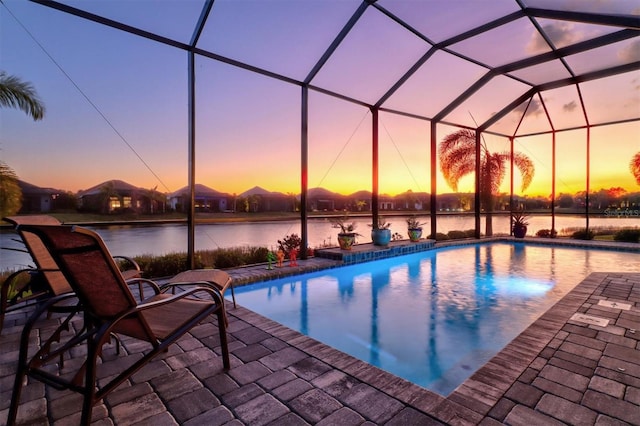 pool at dusk featuring an outdoor pool, glass enclosure, and a patio