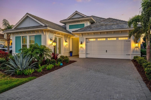 view of front of property featuring stucco siding, an attached garage, and driveway