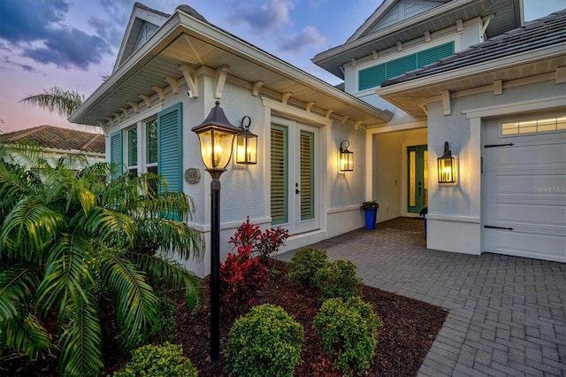 property entrance with a garage and stucco siding