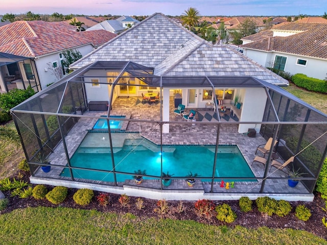 pool at dusk with a patio, an outdoor pool, and a lanai