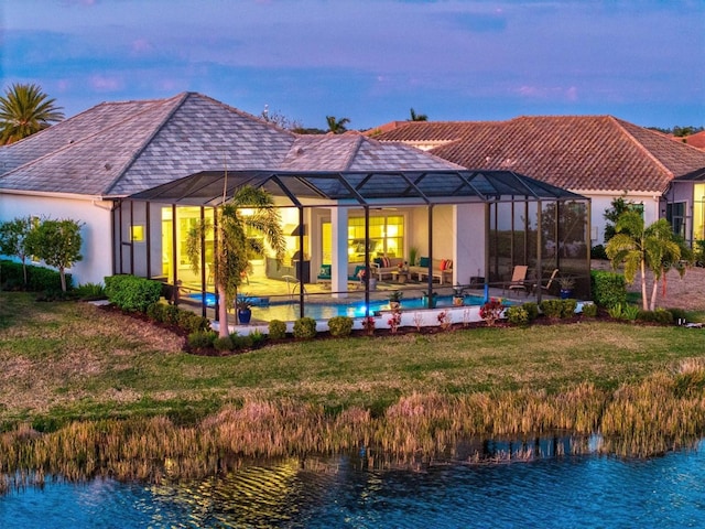 back of property with stucco siding, a lawn, an outdoor pool, a lanai, and a patio area