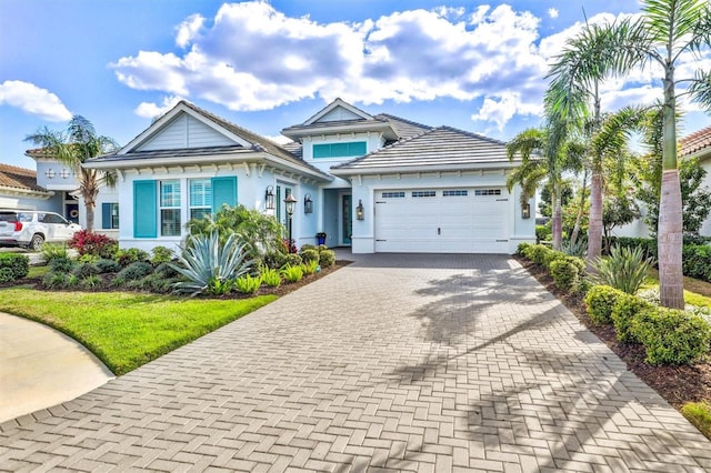 view of front of property with stucco siding, an attached garage, a tile roof, and decorative driveway