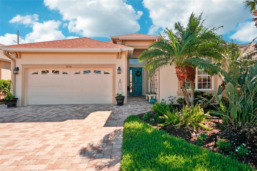 view of front facade featuring a garage, decorative driveway, and stucco siding