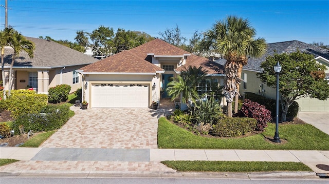 view of front of property featuring stucco siding, an attached garage, driveway, and roof with shingles