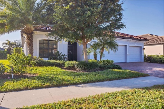 mediterranean / spanish home with decorative driveway, stucco siding, an attached garage, and a tiled roof