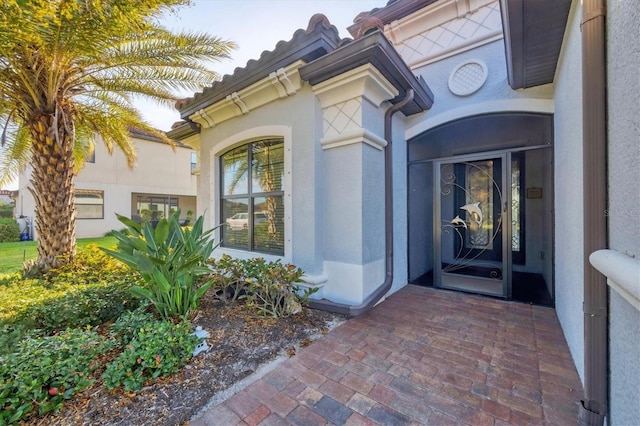 view of exterior entry with stucco siding and a tile roof