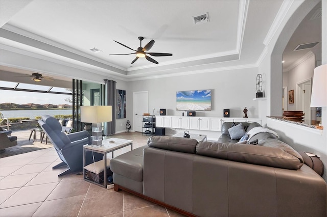 living area with a tray ceiling, visible vents, and a ceiling fan