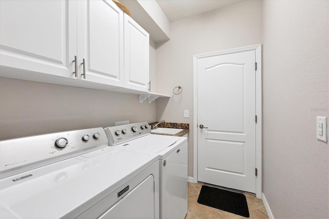 washroom featuring baseboards, washing machine and clothes dryer, light tile patterned flooring, cabinet space, and a sink