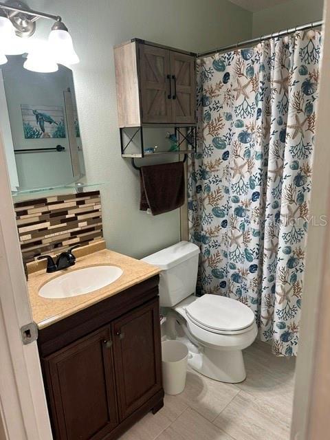 bathroom featuring vanity, decorative backsplash, toilet, and a shower with curtain