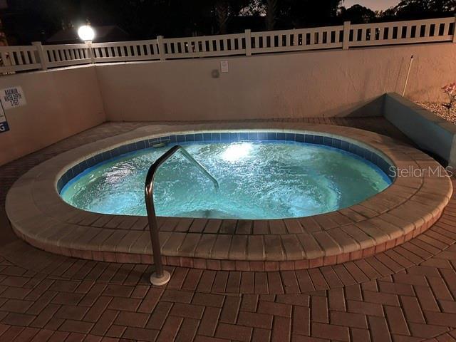 view of pool with a community hot tub and fence