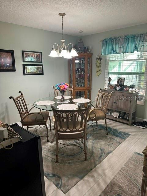 dining space featuring a chandelier, a textured ceiling, and wood finished floors