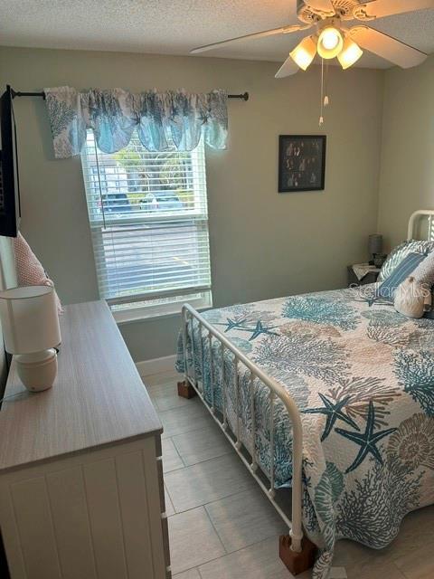 bedroom with baseboards, a textured ceiling, and ceiling fan