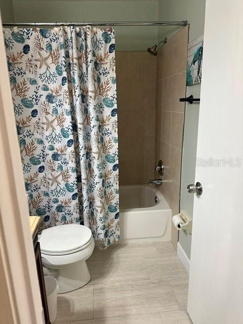 bathroom with wood finished floors, toilet, shower / bath combo, and vanity