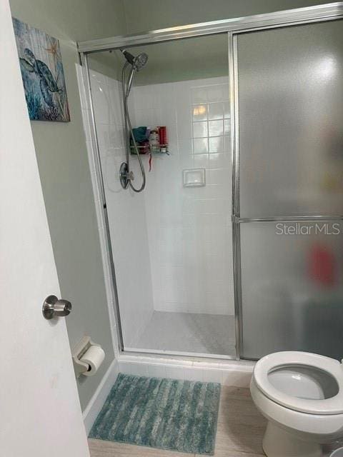 bathroom featuring toilet and a shower stall